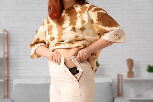 Image of woman trying to do her trousers up after pregnancy weight gain High Wycombe