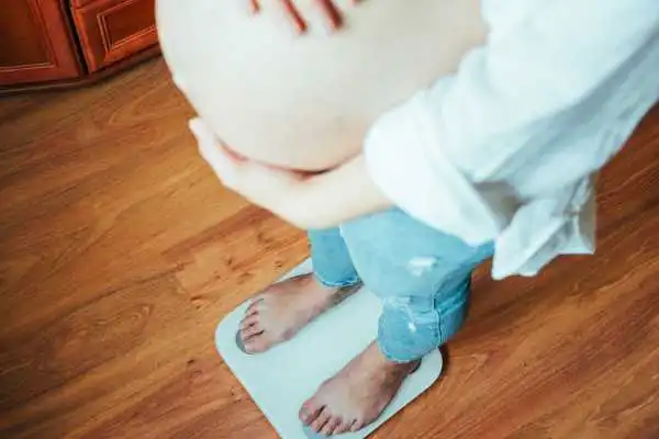 Image of woman weighing herself and experiencing weight gain through pregnancy High Wycombe